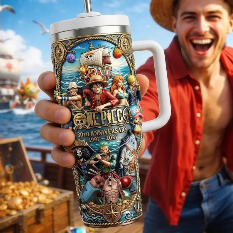 May include: A stainless steel tumbler with a white handle and lid, featuring a colorful illustration of characters and a ship from the "One Piece" anime series. The tumbler commemorates the 30th anniversary from 1997-2027.