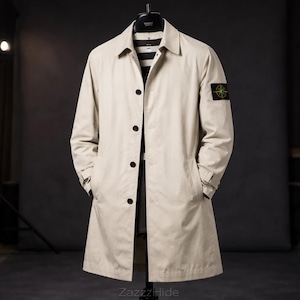 May include: A beige trench coat with a classic design, featuring a collared neckline, button-down front, and side pockets. The coat has a small patch on the upper left sleeve. The coat is hanging on a black hanger.