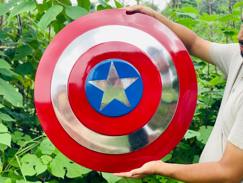 May include: A round shield in red, white, and blue, featuring a silver star at its centre. The shield has a glossy finish. It is a replica of Captain America's shield.