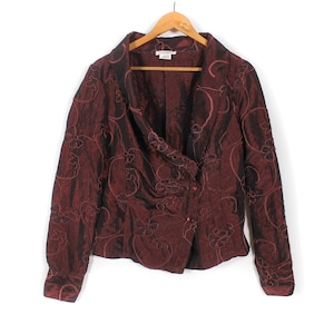 May include: A burgundy blazer with a floral pattern, hanging on a wooden hanger. The jacket has a draped neckline and a single-button closure. The fabric has a subtle sheen.