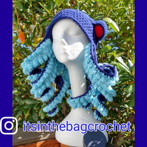 May include: A blue and turquoise crocheted octopus hat with red accents. The hat is on a white mannequin head. The Instagram handle "itsinthebagcrochet" is visible in the bottom left corner of the image.