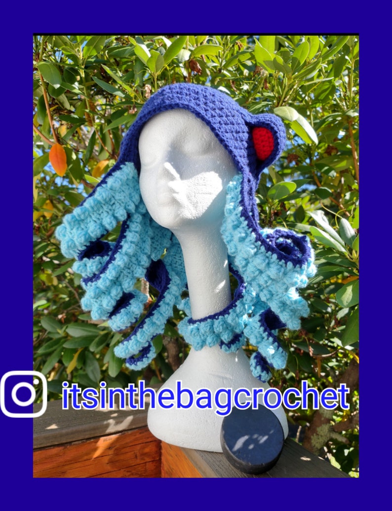 May include: A blue and turquoise crocheted octopus hat with red accents. The hat is on a white mannequin head. The Instagram handle "itsinthebagcrochet" is visible in the bottom left corner of the image.