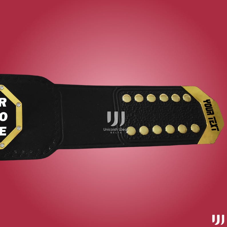 May include: Black leather championship belt with gold accents. The belt features gold studs and a gold plate with the text "YOUR TEXT". The manufacturer's logo is also visible.