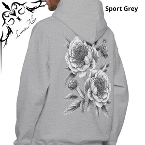 K&ouml;nnte beinhalten: Sportgrauer Kapuzenpullover mit gro&szlig;em schwarz-wei&szlig;em Blumendesign auf dem R&uuml;cken. Der Kapuzenpullover hat eine Kapuze mit Kordelzug und eine K&auml;ngurutasche. Der Markenname "Luna Alla" ist auf der Vorderseite aufgedruckt.