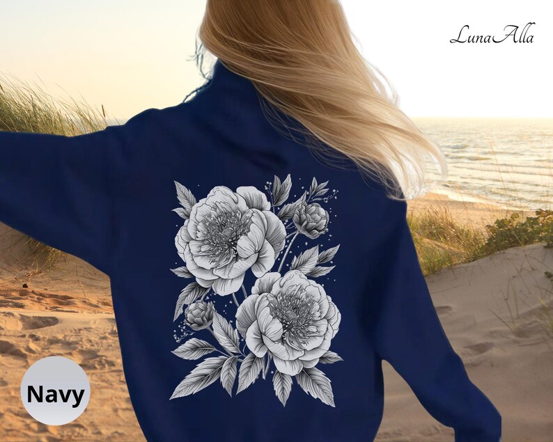 K&ouml;nnte beinhalten: Marineblaues Sweatshirt mit einem schwarz-wei&szlig;en Blumendesign auf dem R&uuml;cken, das Pfingstrosen und Bl&auml;tter zeigt. Das Wort "Navy" befindet sich in einem wei&szlig;en Kreis unten links. Der Markenname "Luna Alla" steht oben rechts.