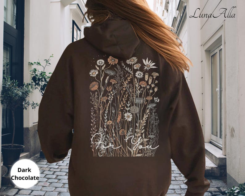 May include: Dark chocolate-colored hoodie with a floral design on the back. The design features various flowers and foliage in neutral tones, with the words "For You" in a cursive font. The hoodie has a hood and a relaxed fit.