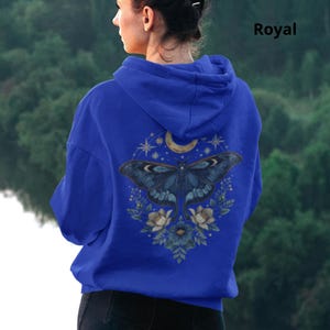 May include: A royal blue hooded sweatshirt featuring a graphic on the back of a large moth surrounded by flowers, stars, and a crescent moon. The word Royal is printed in the upper right corner of the image above the hooded garment.