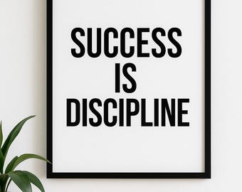 May include: A framed print with the words "SUCCESS IS DISCIPLINE" in bold black letters. The frame is black, and the background is white. A small plant in a white pot, a small bowl, and a vase are on a wooden surface.