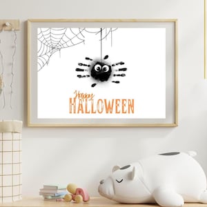 Pode incluir: Uma impressão emoldurada com tema de Halloween com uma aranha preta feita de impressões de mãos e olhos arregalados. Uma teia de aranha está no canto superior esquerdo. As palavras "Happy Halloween" estão em laranja abaixo.