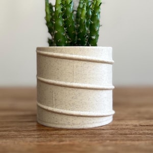 Zadie - Maceta con efecto piedra color crema y diseño asimétrico: luce diferente desde cualquier ángulo