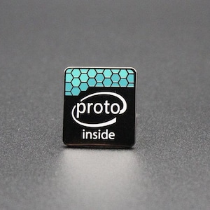 Może przedstawiać: Mała, kwadratowa czarna naklejka z białym napisem "proto" wewnątrz stylizowanego logo Intel. Górna część naklejki ma turkusowy wzór plastra miodu. Słowo "inside" jest wydrukowane poniżej logo.