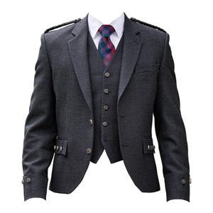 Puede incluir: Un traje de tres piezas gris carbón con camisa de cuello blanco y corbata estampada. El traje incluye chaqueta, chaleco y pantalón. La chaqueta tiene botones decorativos y charreteras. La corbata presenta un diseño de cuadros.