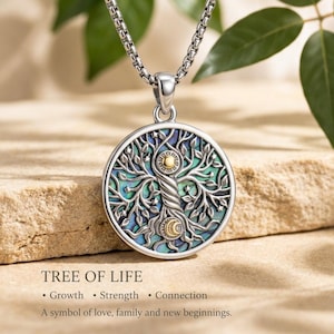 Può includere: Un ciondolo circolare in argento con un design ad albero della vita e un intarsio in conchiglia di abalone iridescente. Il tronco dell'albero incorpora un sole e una mezzaluna dorati. È appeso a una catena d'argento con maglie lucide.