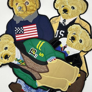 Könnte beinhalten: Eine Sammlung von vier gestickten Aufnähern mit beigen Teddybären in verschiedenen Outfits, darunter ein marineblauer Pullover mit amerikanischer Flagge, ein beiger Trenchcoat, eine grüne Baseballkappe und formelle Kleidung mit schwarzer Jacke.