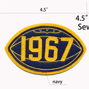May include: An oval-shaped sew-on patch featuring a navy blue football design with yellow embroidery. The number 1967 is stitched in yellow in the center. The patch measures 4.5 inches by 2.8 inches as indicated by the text.
