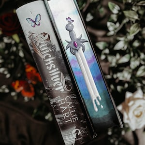 May include: Two hardcover books with decorative covers. One features the title "Quicksilver" and the author "Callie Hart" with a butterfly. The other book has a sword design with a purple gem and a butterfly.