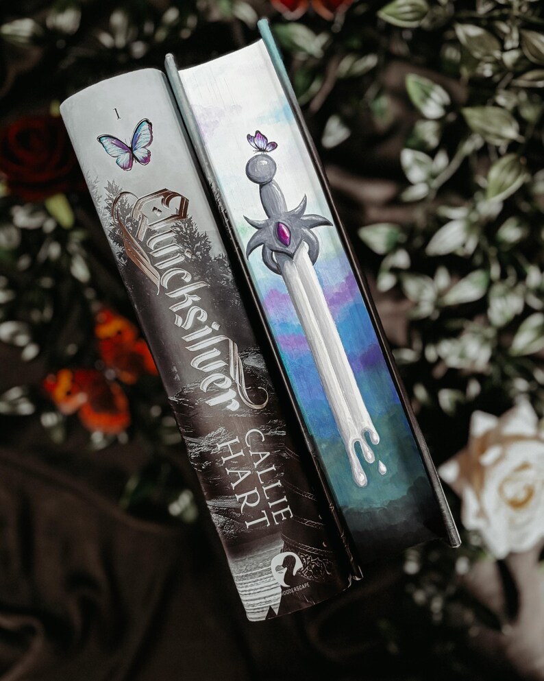 May include: Two hardcover books with decorative covers. One features the title "Quicksilver" and the author "Callie Hart" with a butterfly. The other book has a sword design with a purple gem and a butterfly.