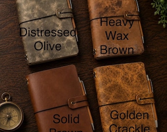 May include: Four rectangular journals with elastic closures and metal accents, each holding a pen. The covers feature distinct textures labeled Distressed Olive, Heavy Wax Brown, Solid Brown, and Golden Crackle. A round brass compass is visible.