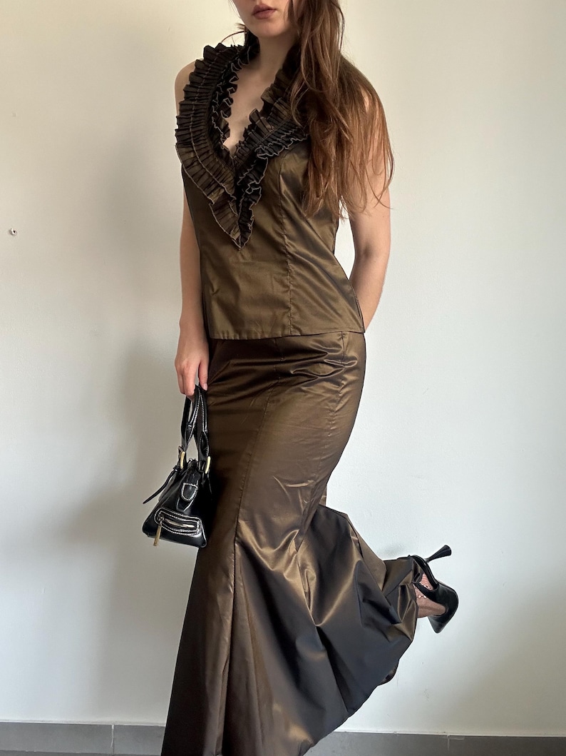 Bronze satin evening set styled in a full outfit view with a dramatic flared skirt and structured ruffle top. A glamorous vintage-inspired look for formal parties, dinners or going-out style.