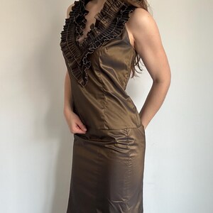 Side view of the Vera Mont satin skirt set with a fitted sleeveless top, pleated ruffle collar and matching long skirt. The bronze sheen makes it a statement evening outfit for vintage glam styling.