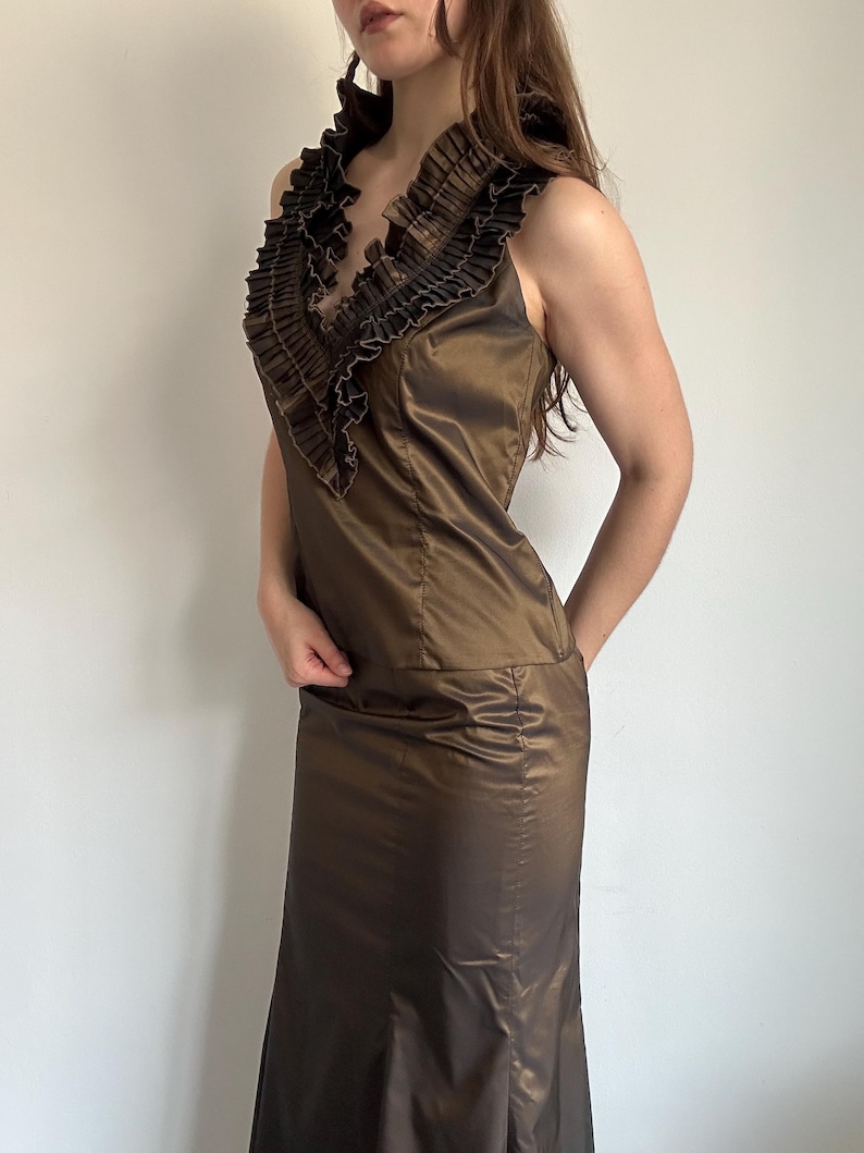 Side view of the Vera Mont satin skirt set with a fitted sleeveless top, pleated ruffle collar and matching long skirt. The bronze sheen makes it a statement evening outfit for vintage glam styling.