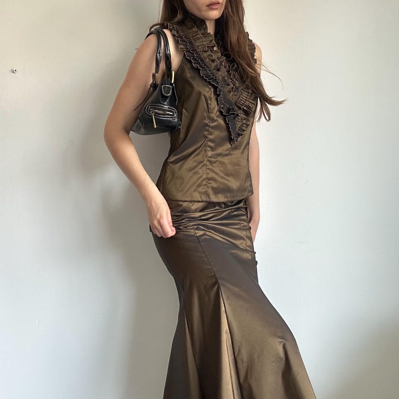 Front view of the Vera Mont bronze satin set showing the fitted ruffle neckline top and matching long skirt. The glossy fabric gives the outfit a polished Y2K evening look.