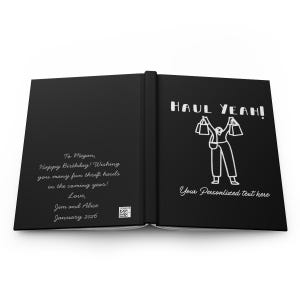 K&ouml;nnte beinhalten: Schwarzes Notizbuch mit dem Text "HAUL YEAH!" und einer Strichm&auml;nnchenfigur, die Einkaufstaschen h&auml;lt. Auf der linken Seite des Journals steht der Text "To Megan, Happy Birthday! Wishing you many fun thrift hauls in the coming year! Love, Jim and Alice January 2026."