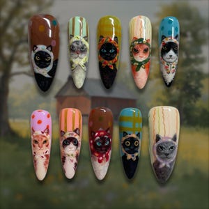 Puede incluir: Un conjunto de diez uñas postizas en forma de almendra con retratos pintados a mano de gatos que llevan pañuelos estampados de colores. Cada uña muestra un rostro felino único con distintos colores de pelaje, expresiones y fondos vibrantes.