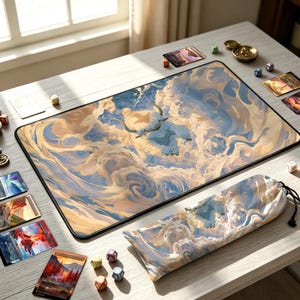 May include: A rectangular playmat and a matching fabric drawstring bag featuring a blue and cream-coloured illustration of a flying bison creature amidst swirling clouds. The set is surrounded by various small polyhedral dice and rectangular cards.