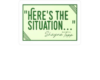 May include: A rectangular sticker with a light green background and a dark green border. The text "HERE'S THE SITUATION..." is in dark green, with the name "Shayne Topp" below in a script font. The sticker has a simple, clean design.