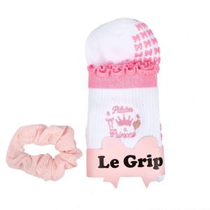May include: White and pink Pilates socks with a ruffled cuff and bow accents, paired with a matching pink scrunchie. The socks feature the text "Pilates Princess" and the brand name "Le Grip".