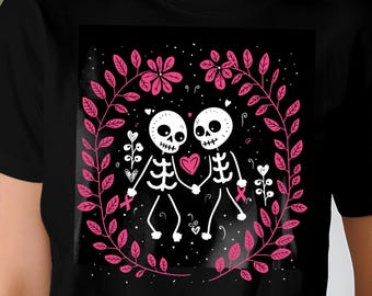 May include: Black t-shirt featuring a graphic of two skeleton figures holding hands, with a pink heart between them. The design is surrounded by a wreath of pink leaves and flowers, set against a black background.