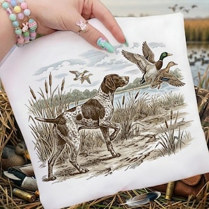 May include: White square pillow with a hunting scene. A brown and white dog stands near tall grass, with ducks flying overhead. The illustration is in shades of brown, green, and blue.