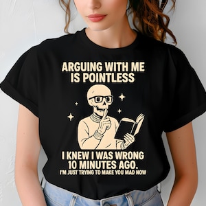 以下が含まれることがあります： 「ARGUING WITH ME IS POINTLESS」のテキストと、メガネをかけた骸骨が本を持っているイラストがプリントされた黒いTシャツ。「I KNEW I WAS WRONG 10 MINUTES AGO. I'M JUST TRYING TO MAKE YOU MAD NOW.」の文字も含まれています。
