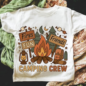 May include: White t-shirt with a camping-themed graphic. The design features a campfire, trees, and signs that read "Fires", "Fun", and "Friends". A lantern, backpack, and sleeping bag are also included. The words "Camping Crew" are at the bottom.