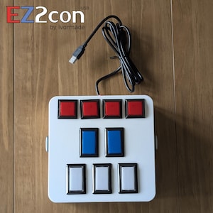 May include: White rectangular control panel with red, blue, and white buttons. The panel has the text "EZ2con by ivormade" in red and black. A black USB cable is connected to the top of the panel.