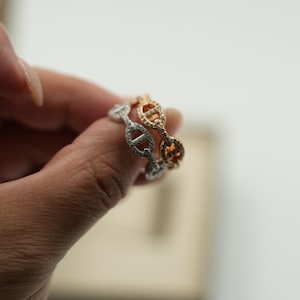 Op de afbeelding: Twee ringen in kettingstijl, één zilverkleurig en één roségoudkleurig, worden van dichtbij getoond. De zilverkleurige ring is bezet met kleine, heldere steentjes. De roségoudkleurige ring heeft een vergelijkbaar ontwerp. De ringen worden gepresenteerd tegen een zachte, neutrale achtergrond.