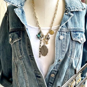 Long locket necklace with a tangle of vintage and handmade charms on vintage style matt gold mariner chain