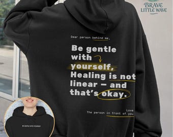 May include: Black hoodie with the text "Dear person behind me, Be gentle with yourself, Healing is not linear - and that's okay." The hoodie also has a small image of a hoodie with the text "Be gentle with yourself."