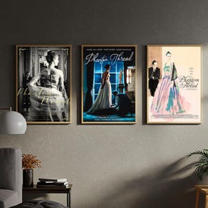 Puede incluir: Tres carteles enmarcados de la película "Phantom Thread" cuelgan de una pared gris. Los carteles presentan imágenes de las estrellas de la película y el título de la película. Los marcos son dorados y los carteles son rectangulares.
