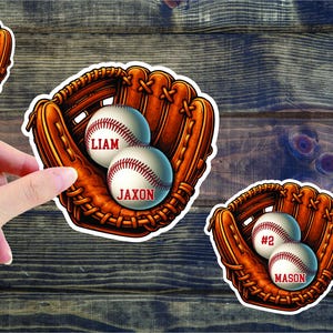 May include: Baseball-themed stickers featuring baseballs inside brown gloves. Each baseball has a name and number in red. The stickers are on a wooden background. The names include Ash, Liam, Jaxon, and Mason.