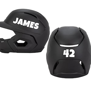 May include: Two black baseball helmets. One helmet has the name "JAMES" in white lettering. The other helmet has the number "42" in white. Both helmets are shown against a white background.