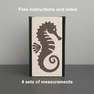 Op de afbeelding: Een decoratief houten blok met een donkerbruin zeepaardje silhouet op een lichtbeige achtergrond. Het blok is omlijst met donkergroene en zwarte randen. Tekst bovenaan luidt "Free instructions and video" en onderaan "4 sets of measurements."