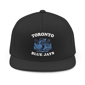 Pode incluir: Boné de beisebol preto com o logotipo do Toronto Blue Jays. O logotipo apresenta um pássaro azul com um bastão e uma bola de beisebol, e as palavras "TORONTO BLUE JAYS" em branco.