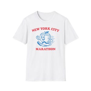 May include: White t-shirt with a blue and red graphic of a running apple character. The text "NEW YORK CITY MARATHON" is printed above and below the apple illustration. A fun, sporty design.