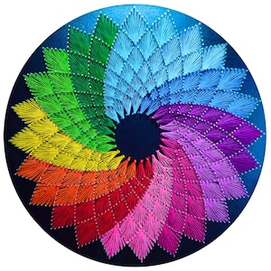 Puede incluir: Una obra de arte textil circular con un vibrante diseño de espiral arcoíris. La obra presenta un espectro de colores que van del rojo al morado, verde y azul. El diseño está creado con hilo y pequeñas cuentas blancas sobre un fondo azul oscuro.