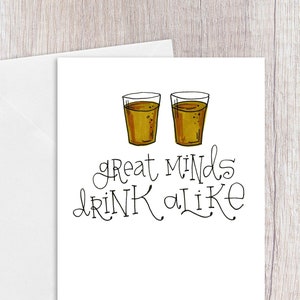 Könnte beinhalten: Eine weiße Karte mit zwei Gläsern brauner Flüssigkeit und dem Text "great minds drink alike".