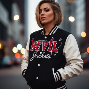 May include: Black varsity jacket with white sleeves. The jacket features the text "DEVIL Jackets" in red and white. The jacket has a striped collar, cuffs, and hem. The jacket has two front pockets and a button-up closure.