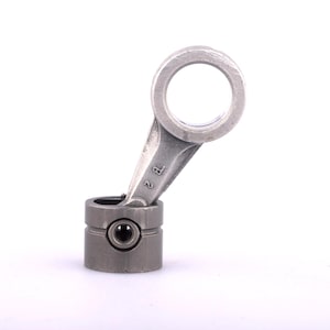 Puede incluir: Una biela de metal gris con una abertura circular en la parte superior y una base cilíndrica. La varilla está en ángulo y la base tiene un pequeño detalle circular oscuro. El número "2 P" está estampado en la varilla.
