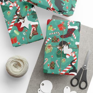 May include: Wrapped gifts with a festive green pattern featuring candy canes, presents, and black cats. Each gift is tied with twine and a tag. A spool of twine, scissors, and blank tags are also visible.
